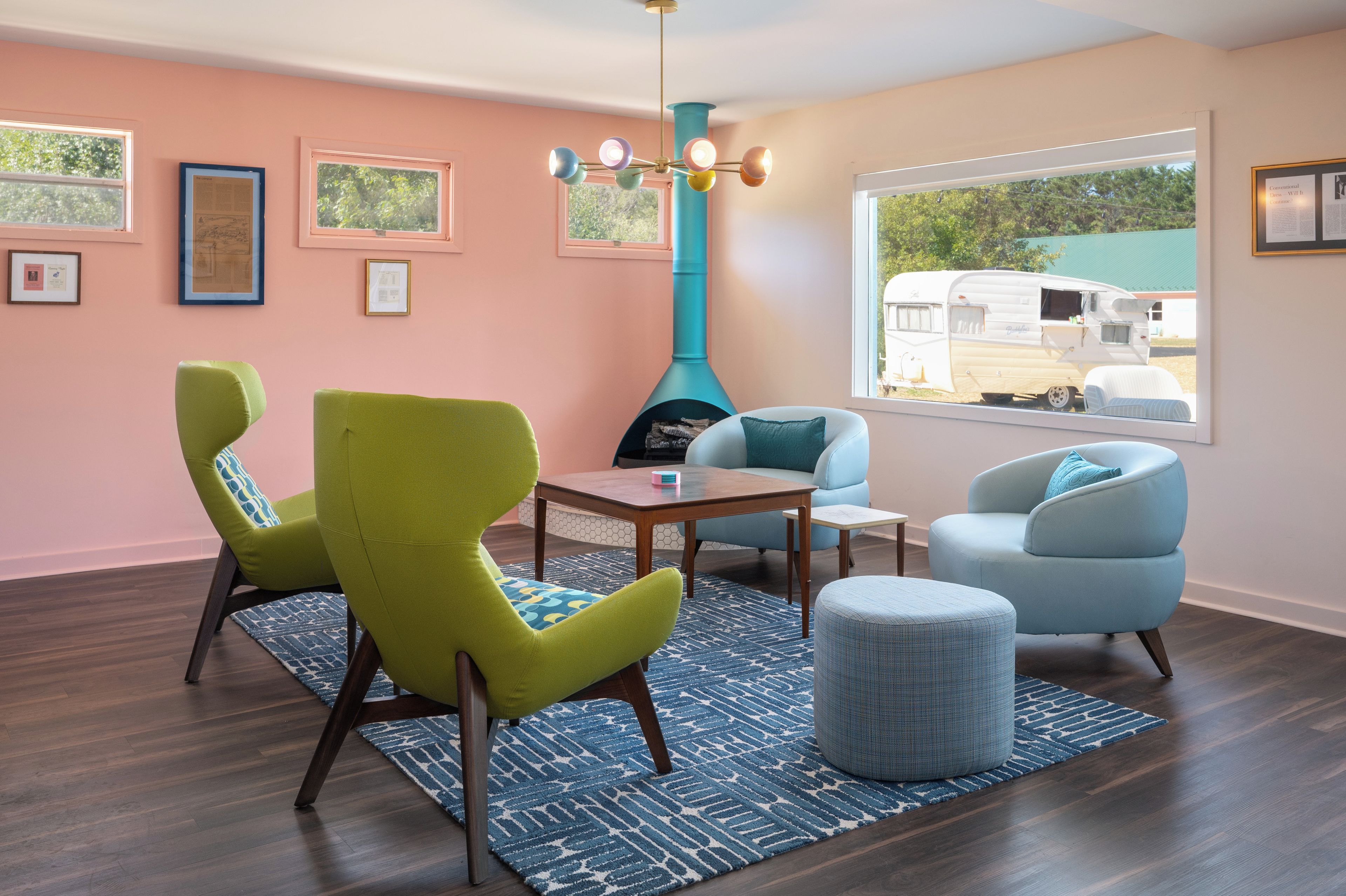 A modern living room with a large window, a teal accent wall, and a dining area.