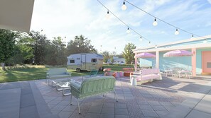 An outdoor patio area with seating, a caravan, and string lights.