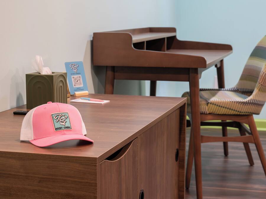 Un bureau en bois, sur lequel on trouve un pot à crayons rose, une boîte de mouchoirs et un panneau avec un code QR.