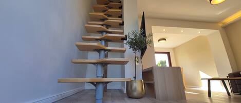 A modern staircase with a unique design, a black doormat with 'HOME' written on it, and a plant in the corner.