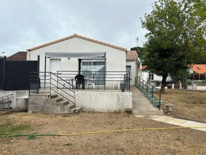 A residential building with a flat roof, a front porch, and a staircase leading to the entrance. - Maison accessible PMR tout confort ,Jardin,proche de la plage et du centre ville (Saint-Brevin-les-Pins)