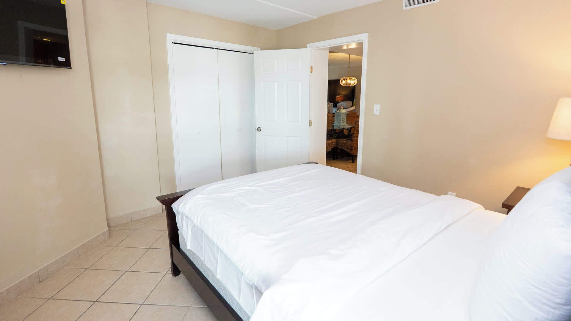 A bedroom with a bed, a wardrobe, and a door leading to a bathroom.