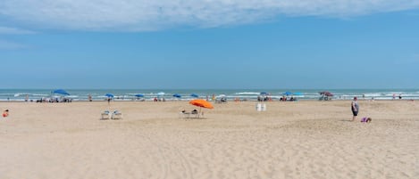 Una extensa playa de arena con sombrillas y sillas de playa.