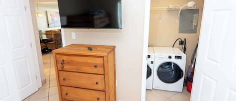 Un lavadero con lavadora, secadora y cómoda de madera con cajones.