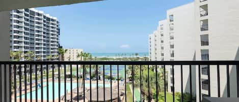 Vista de un hotel con piscina, canchas de tenis y una playa al fondo.