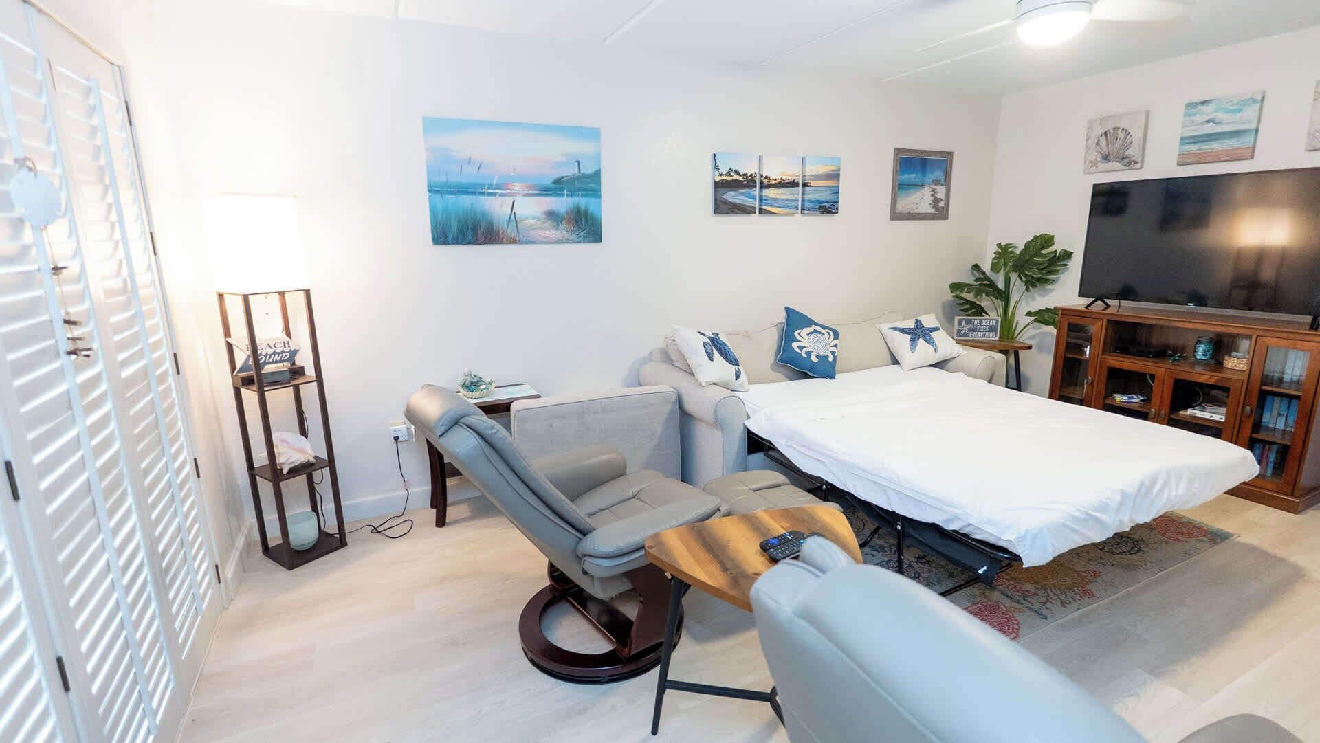 Ein Schlafzimmer mit einem Bett, einem Schreibtisch, einem Sessel, einem Fernseher und Bildern an der Wand.