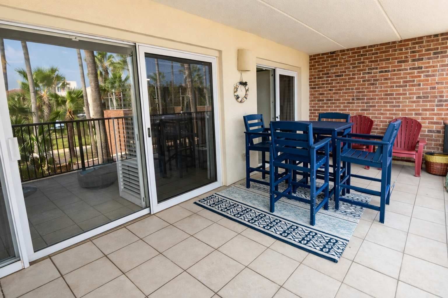 A balcony with a sliding glass door, a table with chairs, and a brick wall.