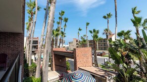 A hotel with multiple-story buildings, palm trees, and a clear blue sky. - 2BR Condo - 2 Pools - Jacuzzi - Steps to Beach SPI (South Padre Island)
