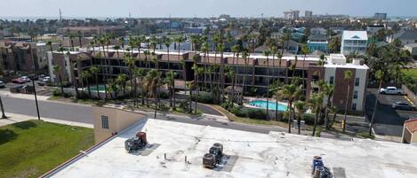 A hotel with a pool, palm trees, and a view of the city.