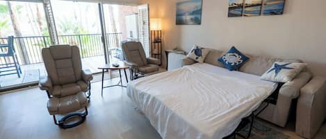 Ein Schlafzimmer mit einem Bett, zwei Sesseln, einem kleinen Tisch und einem Sofa.