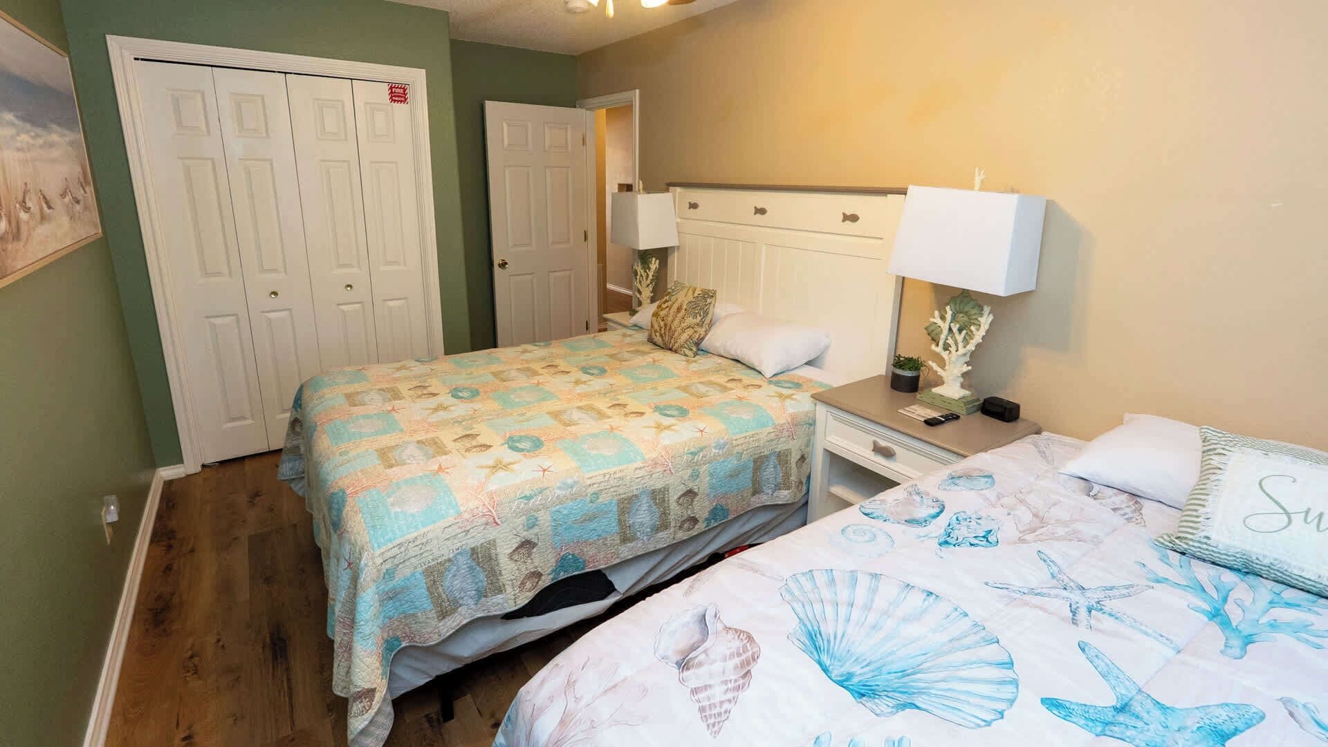 A bedroom with a bed, bedside table, lamp, and a dresser.