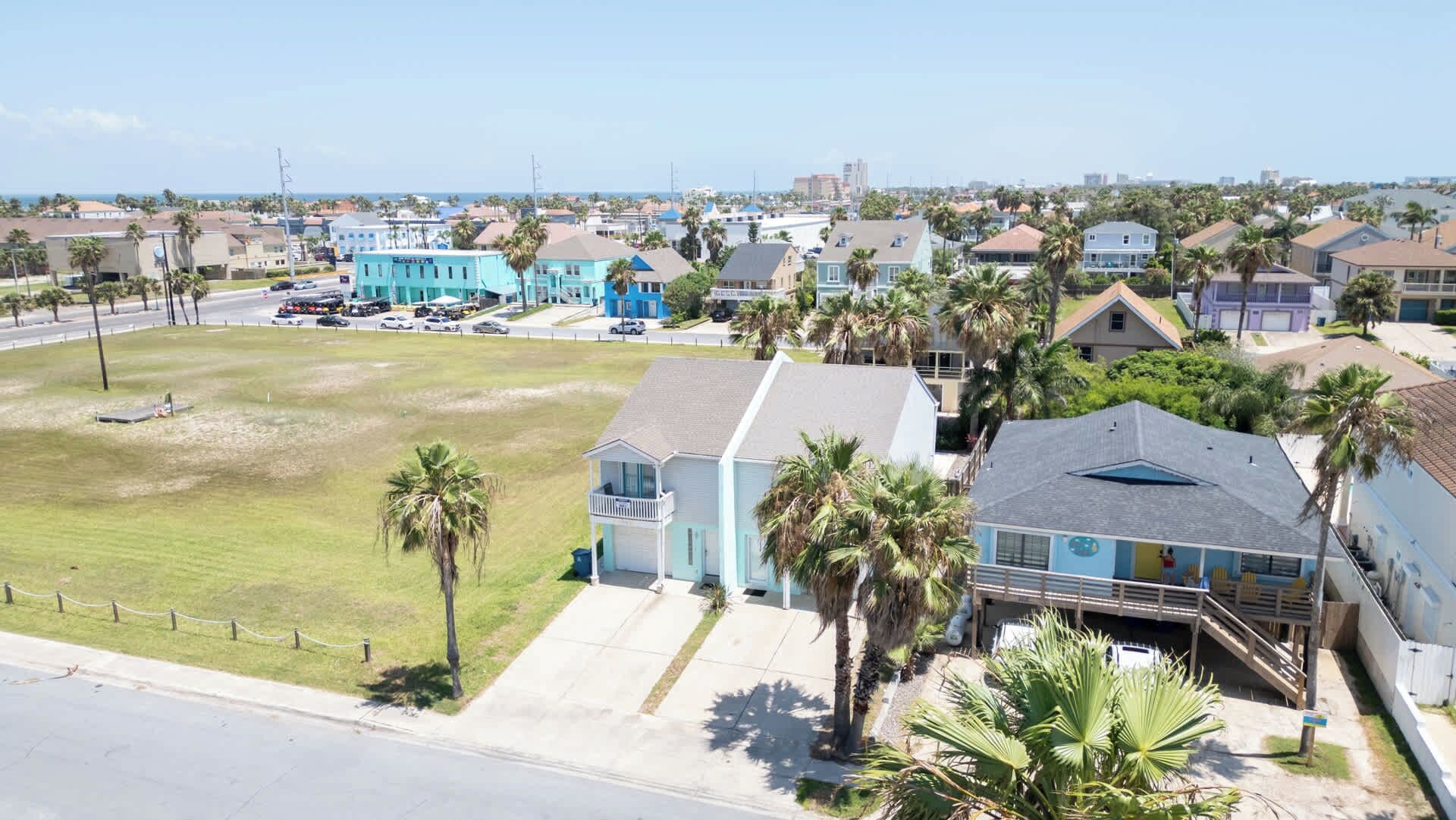 A coastal residential area with houses, a beach, and a clear sky.