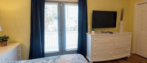 A bedroom with a bed, a dresser, a TV, and a door.