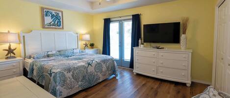 Une chambre à coucher comprenant un lit, des tables de chevet, une commode, un téléviseur et un ventilateur de plafond.