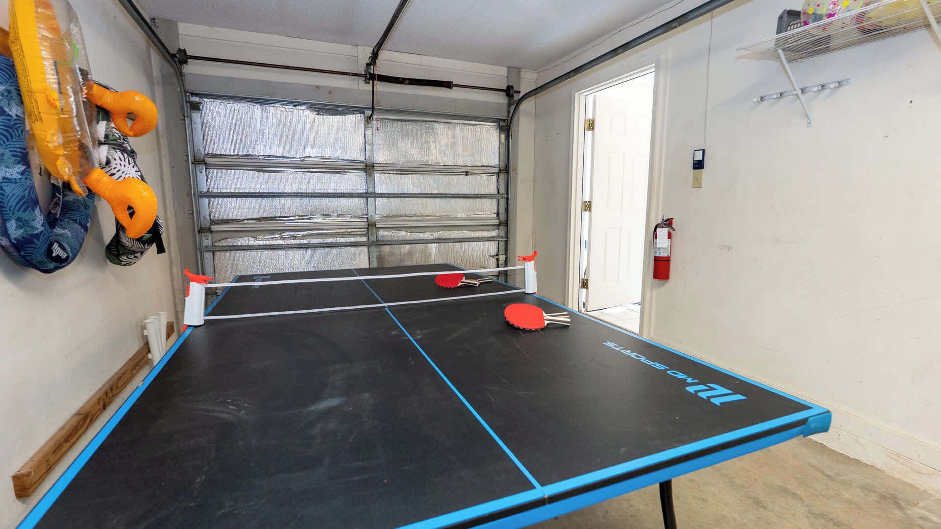 Une table de ping-pong avec un bord bleu, un extincteur et une porte à l’arrière-plan.