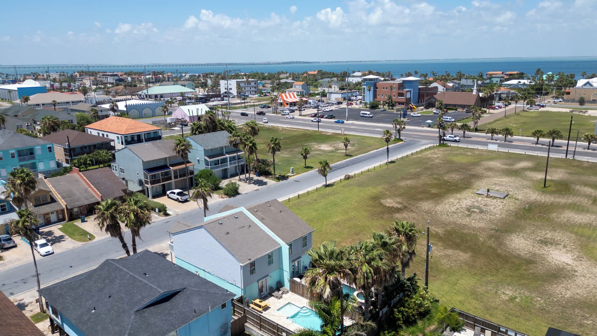 A residential area with houses, a swimming pool, and a view of the ocean.
