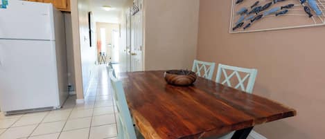 Un coin repas avec une table en bois, des chaises blanches et une décoration murale représentant des poissons.