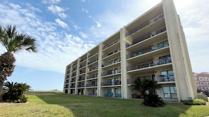 Un hotel de diversos pisos amb balcons, un camp de gespa i palmeres.
