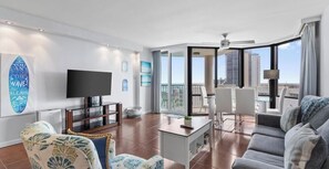 Uma sala de estar moderna com televisão de tela plana, sofá, mesa de centro e varanda com vista para a cidade.