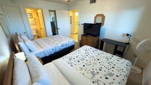 A hotel room with two beds, a TV, a desk, a mirror, and a fan. - 2BR Half Block to Beach, Pool Hot Tub Patio SPI (South Padre Island)