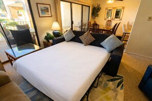 A hotel room with a large bed, a glass table, a seating area with chairs, a dining table, and a plant. - 2BR Half Block to Beach, Pool Hot Tub Patio SPI (South Padre Island)