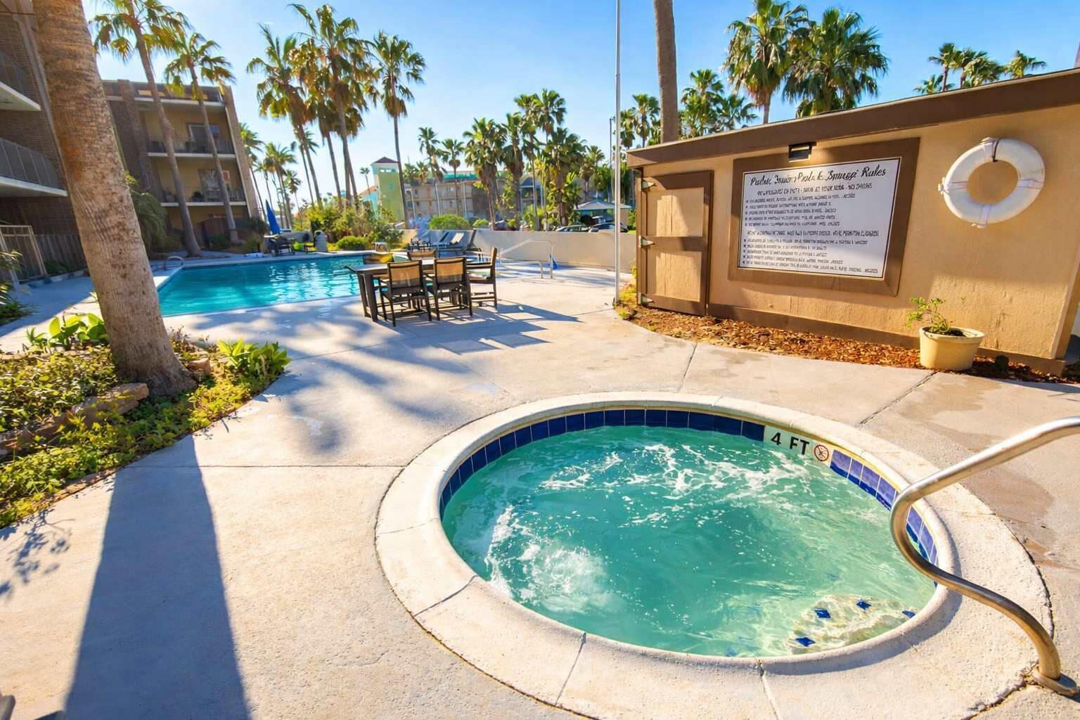 A pool area with a hot tub, lounge chairs, and a lifebuoy on a sunny day.