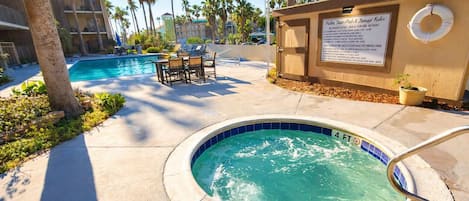 A pool area with a hot tub, lounge chairs, and a lifebuoy on a sunny day.