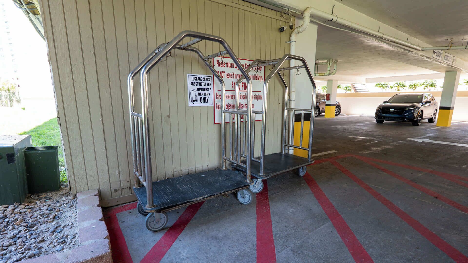A parking garage with luggage carts, a car, and a sign indicating carts are for owners/renters only.