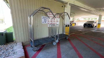 A parking garage with luggage carts, a car, and a sign indicating carts are for owners/renters only.