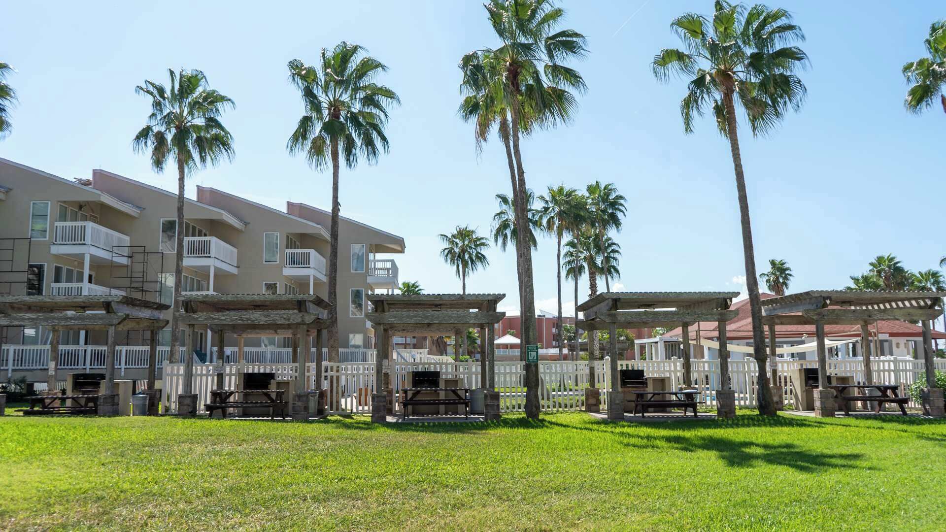 A resort with multiple-story buildings, outdoor seating areas, and palm trees.