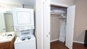 A laundry area with a washer and dryer, a mirror, and a closet with hanging space.
