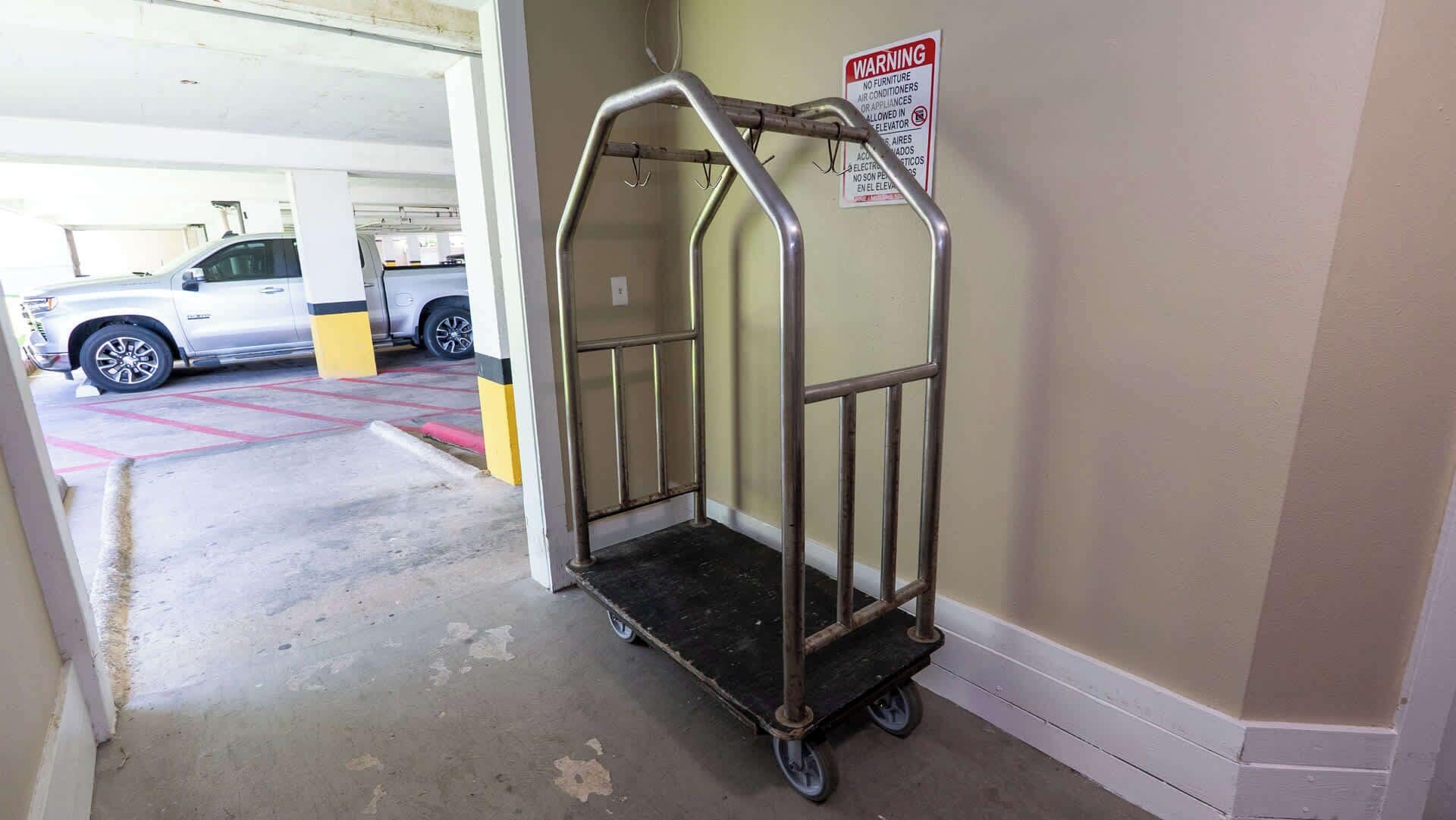 A parking garage with a metal cart and a warning sign on the wall.