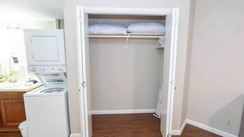 Een wasserette met een wasmachine, droger en een kast met een kledingroede.