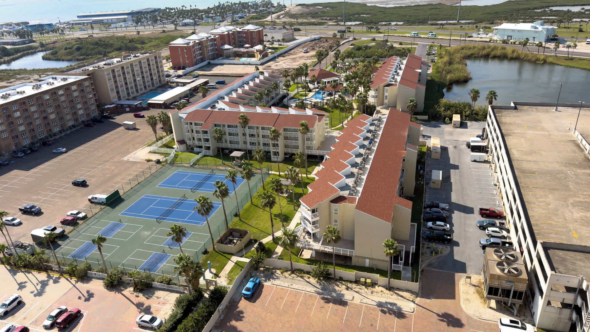 Un hôtel comprenant plusieurs bâtiments, un court de tennis et un parking.