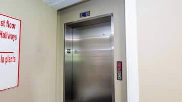 An elevator with a digital display, a fire alarm button, and a sign indicating the location of the first floor hallways and the plant.