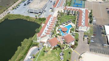 Luchtbeeld van een resort met een zwembad, parkeerplaatsen en een waterlichaam.