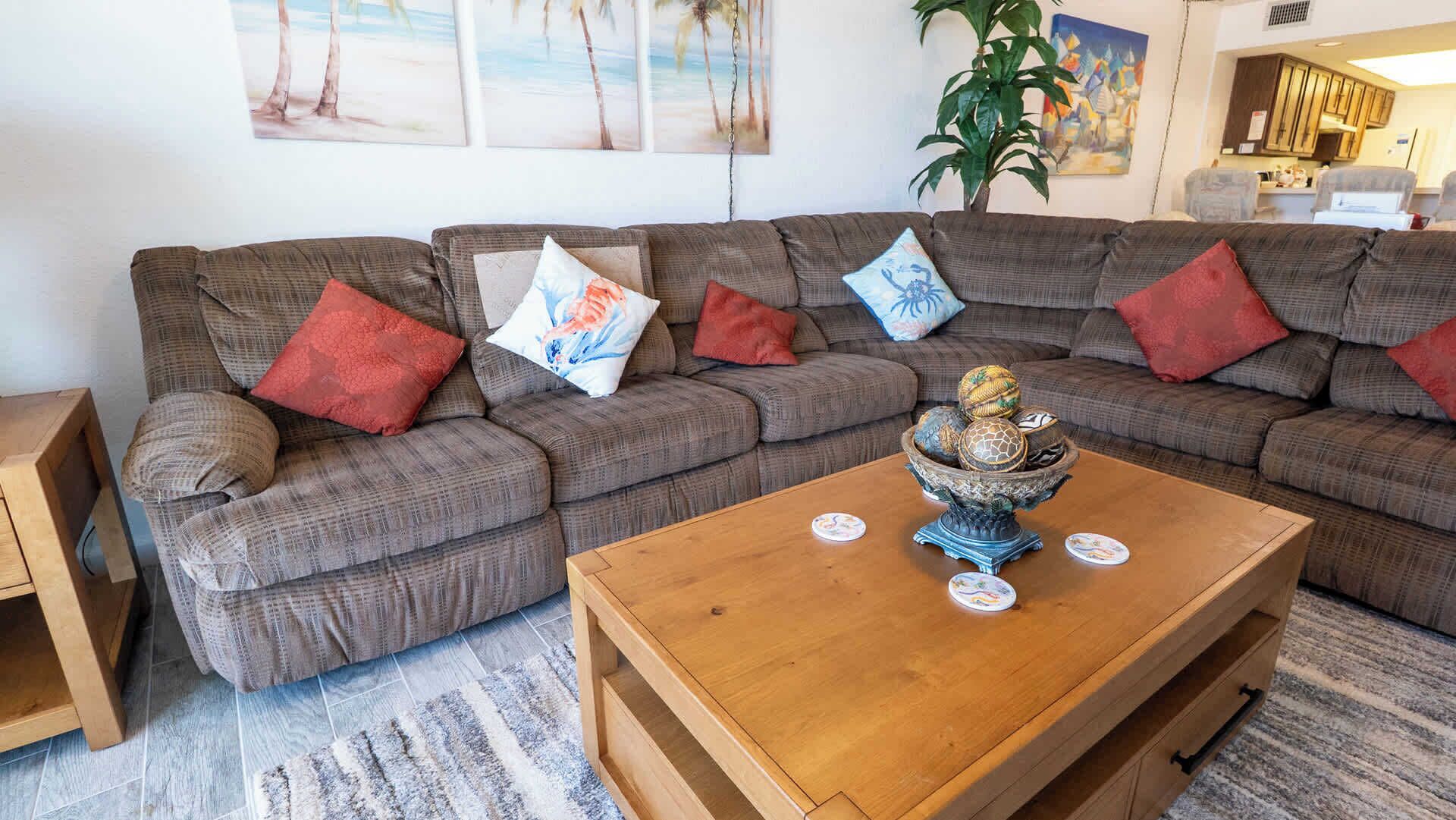 A living room with a sectional sofa, a coffee table, and a plant.