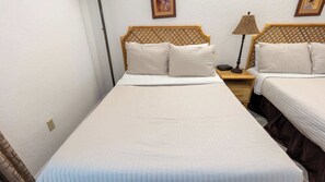 A single-bed room with a wooden headboard, a bedside table with a lamp, and a framed picture on the wall. - Beachfront 2br, 5th Floor Views, Walkable SPI (South Padre Island)