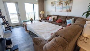 Ein gemütliches Wohnzimmer mit einer Couch, einem Couchtisch, einer Lampe und einem Palmenbild.