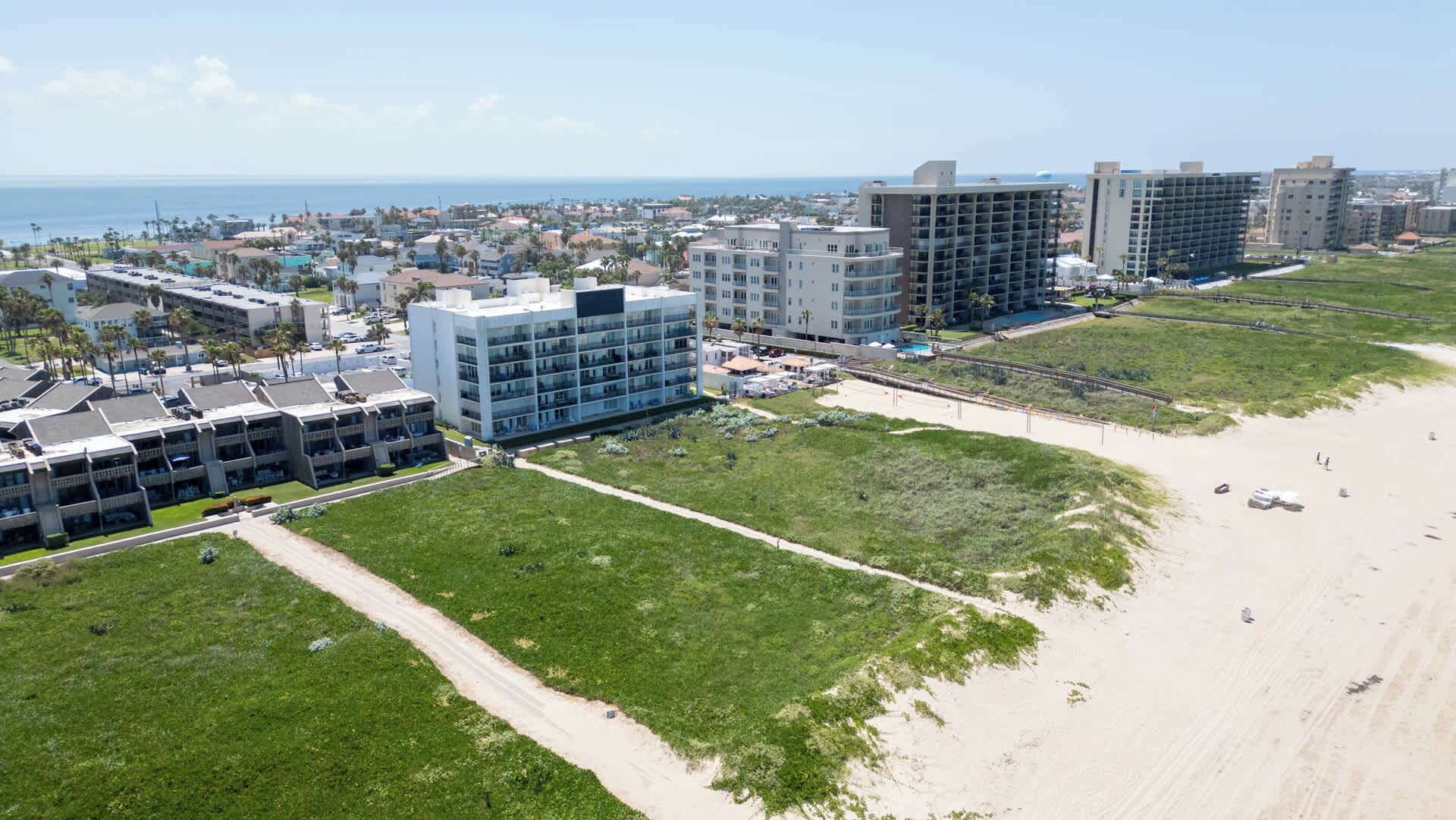 Een kusthotelgebied met meerdere gebouwen, een strand en helder uitzicht op de oceaan.