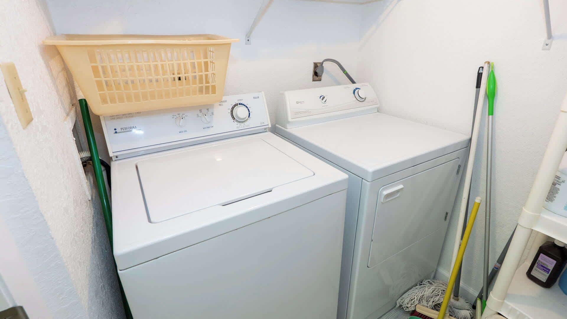 Een wasruimte met twee wasmachines, een droogrek en schoonmaakmiddelen.