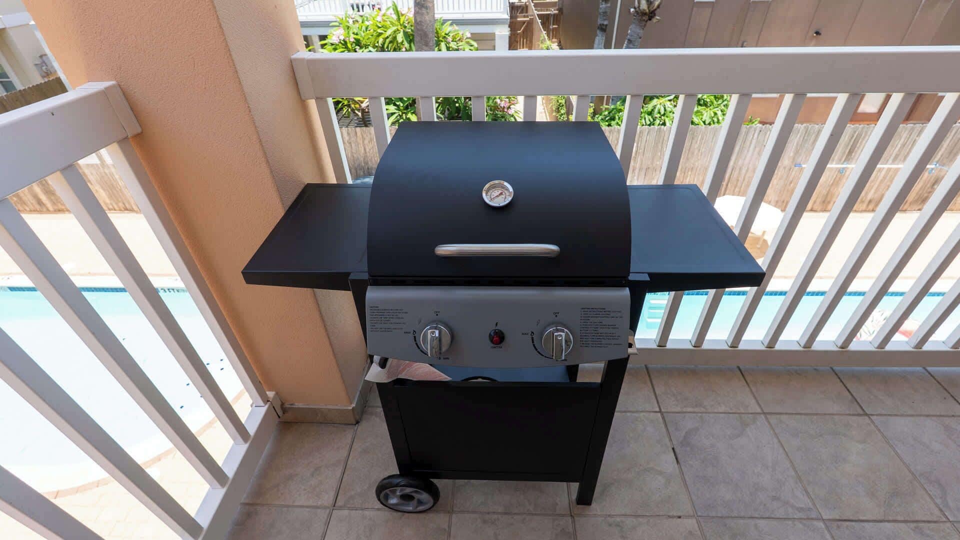 Una parrilla de barbacoa en un balcón, con una piscina al fondo.