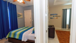 A bedroom with a bed, a door, a dresser, and a ceiling fan. - 2BR Pool, 200 Steps to Beach, High Ceilings SPI (South Padre Island)