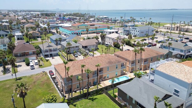 A coastal residential area with multiple-story buildings, a swimming pool, and a view of the ocean. - 2BR Pool, 200 Steps to Beach, High Ceilings SPI (South Padre Island)