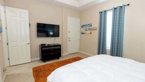 A bedroom with a bed, a TV mounted on the wall, a dresser, and two doors. - 2BR Pool, 200 Steps to Beach, High Ceilings SPI (South Padre Island)