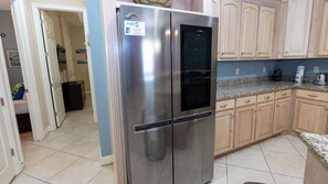 Una cocina con refrigerador de acero inoxidable, armarios de madera y piso de baldosas.