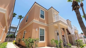 A two-story building with a balcony, a gated entrance, and a clear sky. - 2BR Pool, 200 Steps to Beach, High Ceilings SPI (South Padre Island)