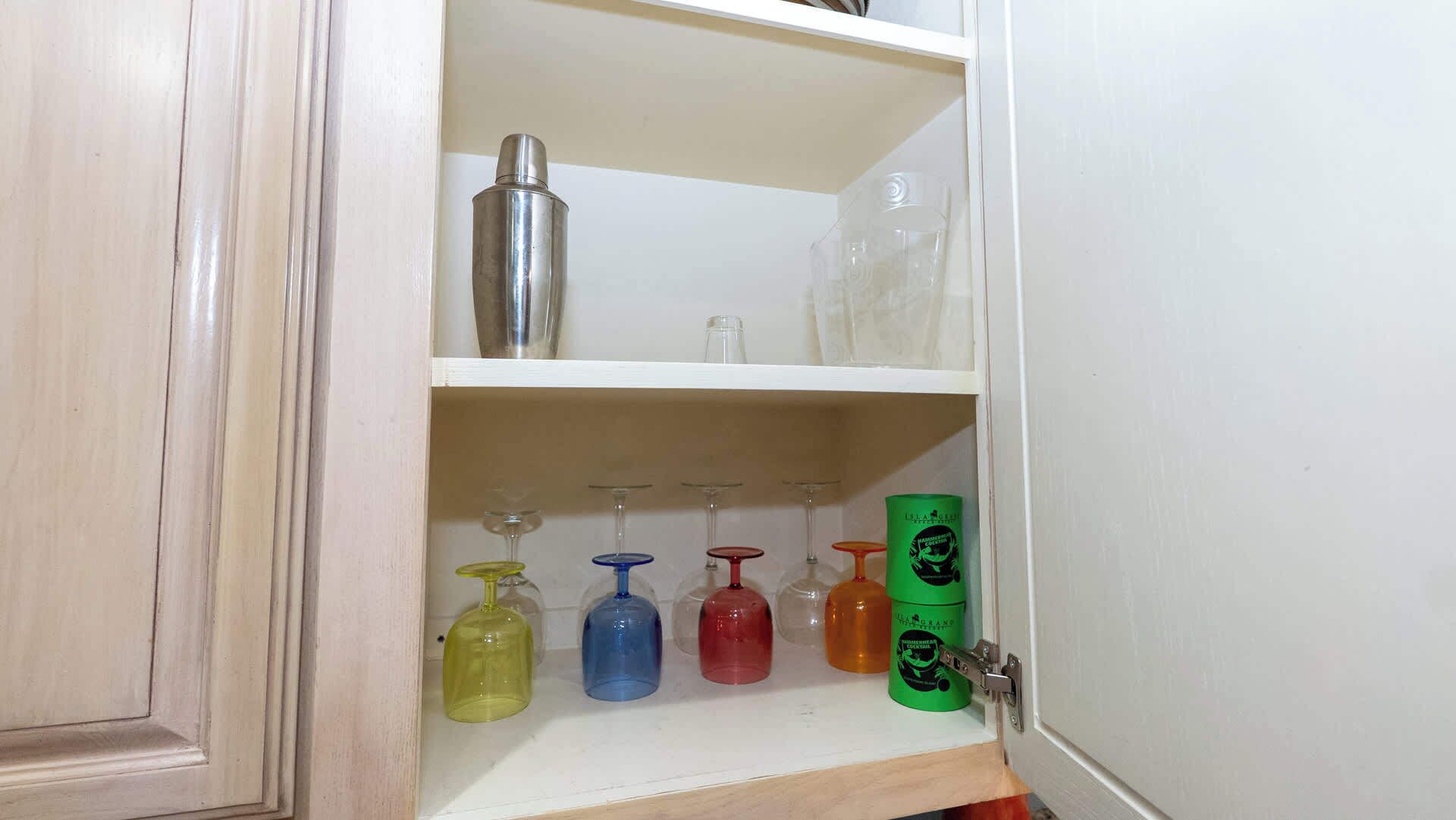 A cabinet with shelves containing various glass bottles and a metal container.