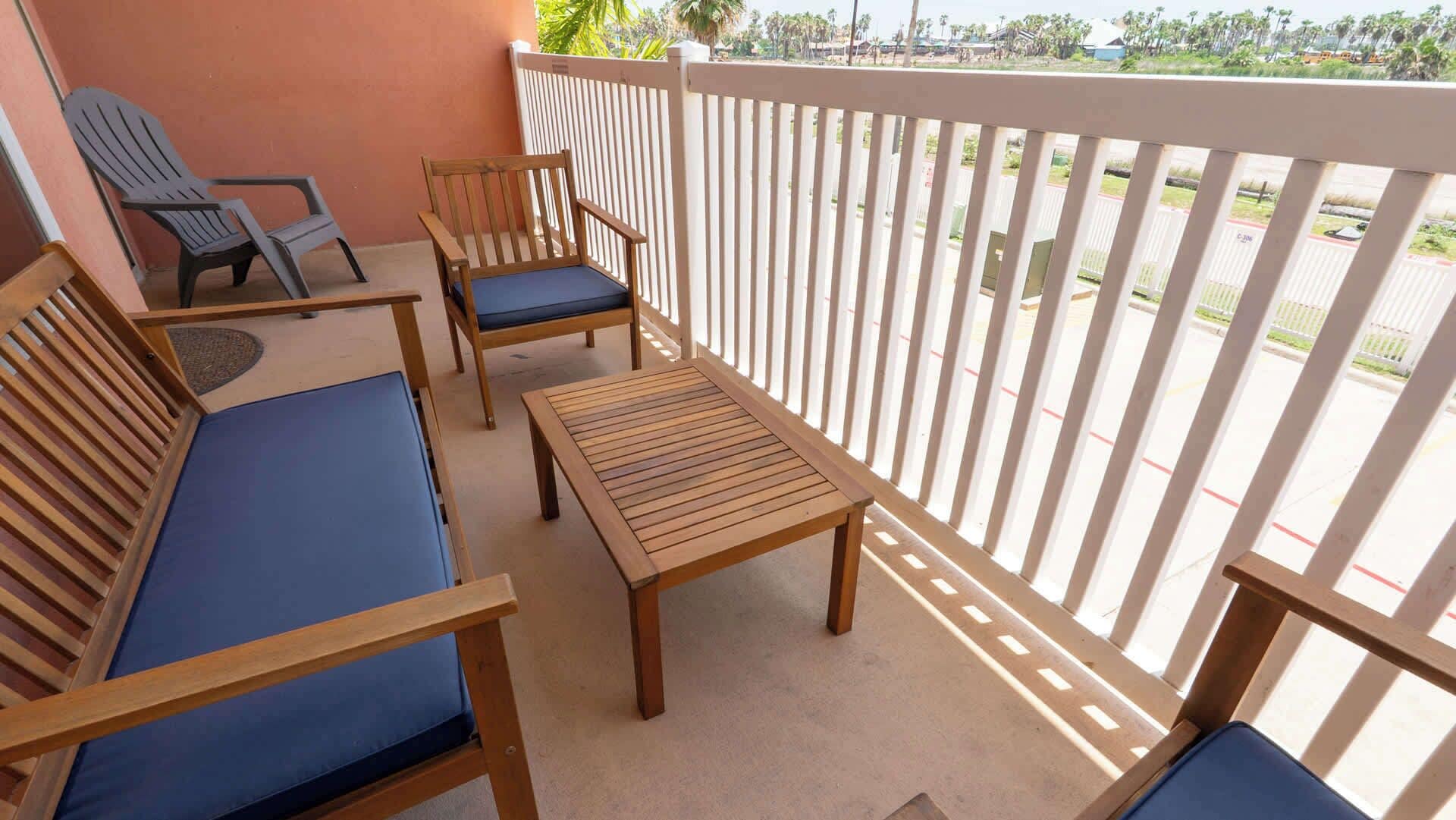 Un balcon doté de mobilier en bois, comprenant un canapé, des fauteuils et une table.