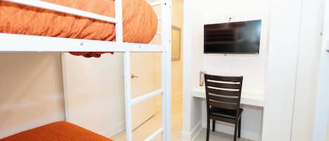 A bunk bed with a desk and chair, a television, and a door.